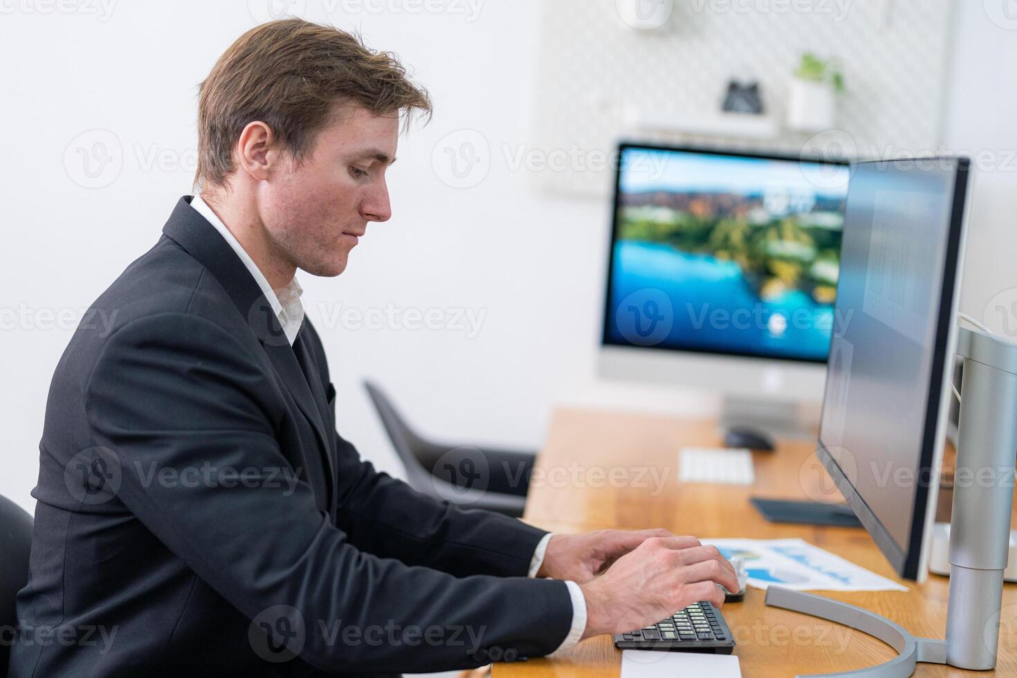 Professional man working at a modern desk in a bright office environment while focused on his tasks photo