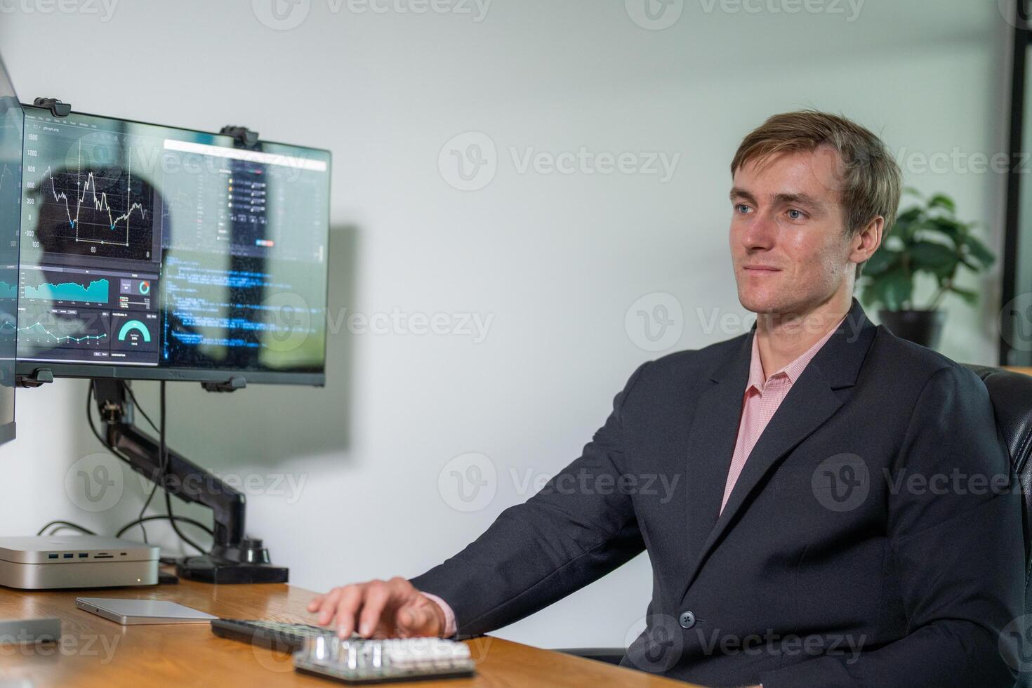 Business professional analyzing data on a dual monitor setup in a modern office environment during daytime photo
