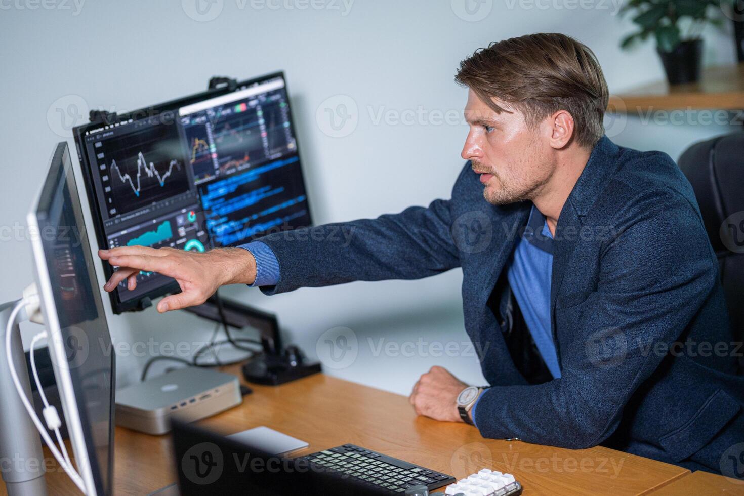 Professional man analyzing data on multiple monitors in modern office setting during daytime photo