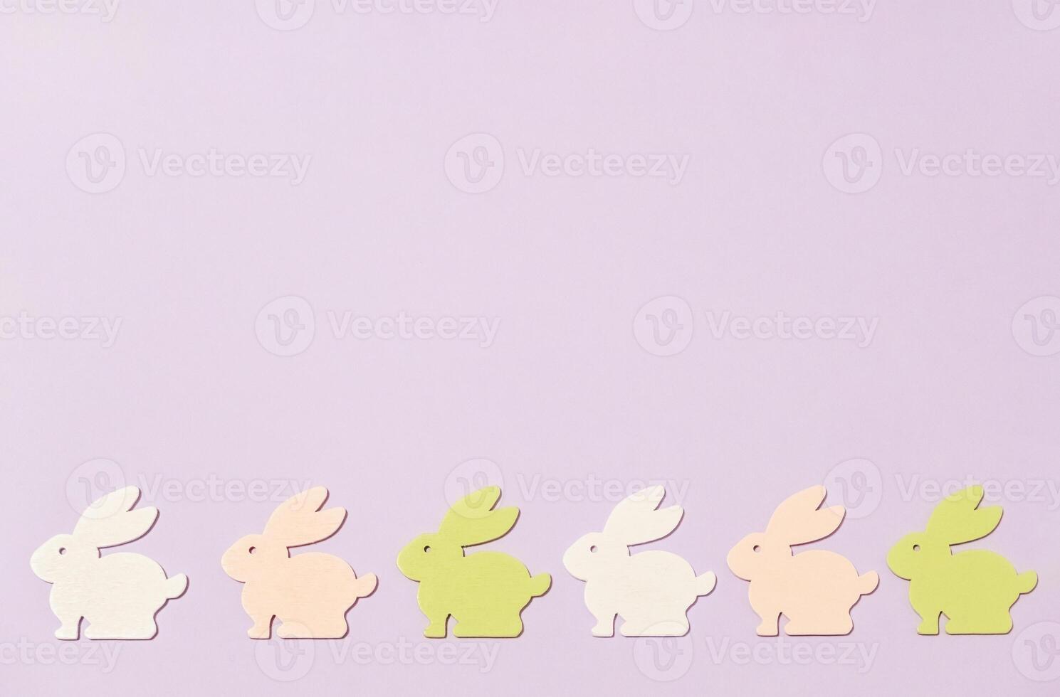 Row of rabbits in different colors are arranged on a purple background photo