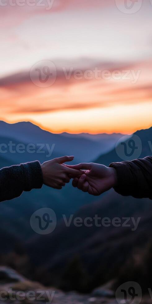 Hands connecting at sunset on a mountain peak photo