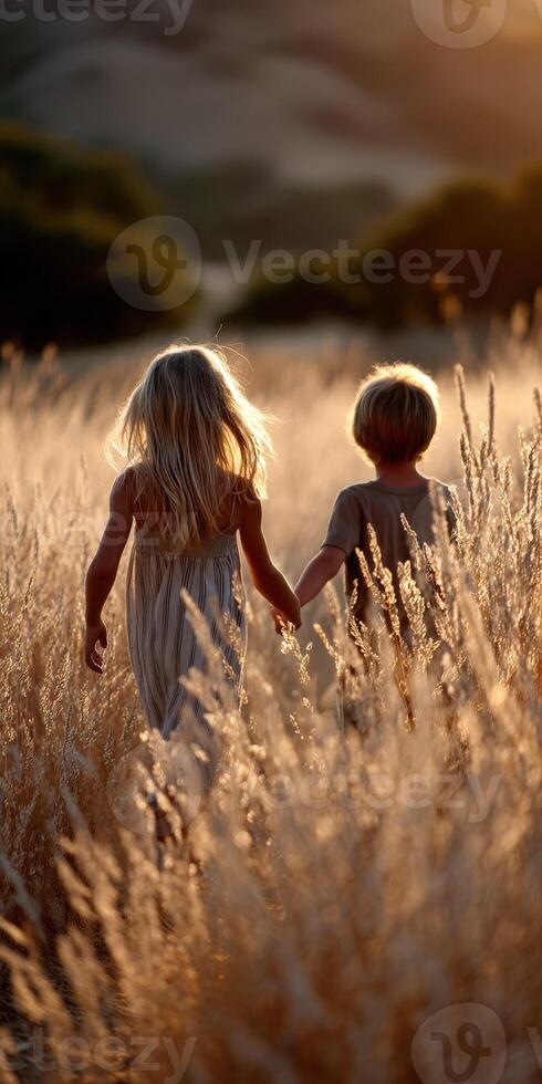 Children explore golden grass field at sunset photo