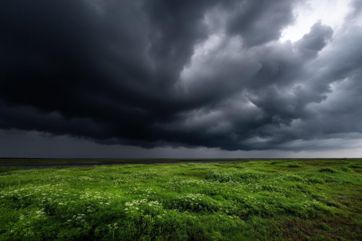 A large field with green grass and dark clouds photo