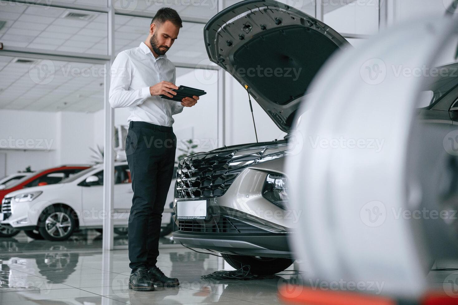 Worker ,in formal clothes is in the auto salon photo