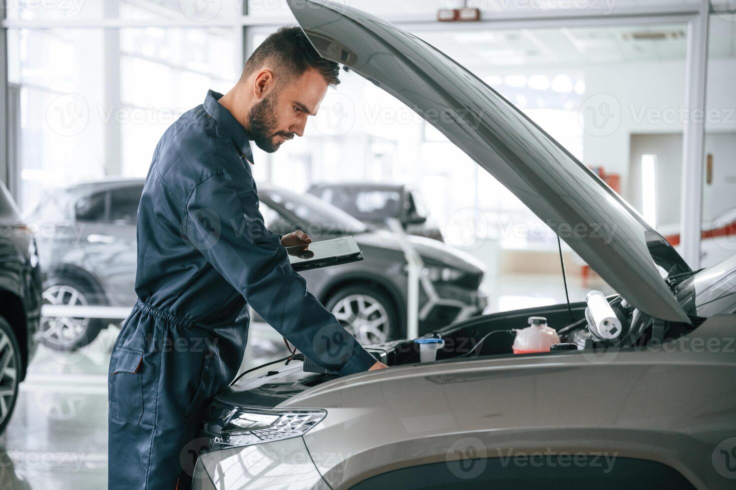 View from the side., Car repairman, is in the garage with automobile photo