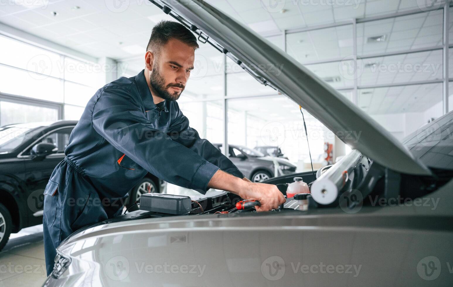 Focused ,on, fixing, the vehicle. Car repairman is in the garage with automobile photo