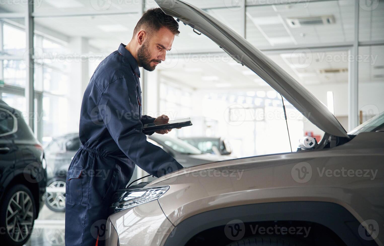 View ,from the ,side. Car repairman is in the garage with automobile photo