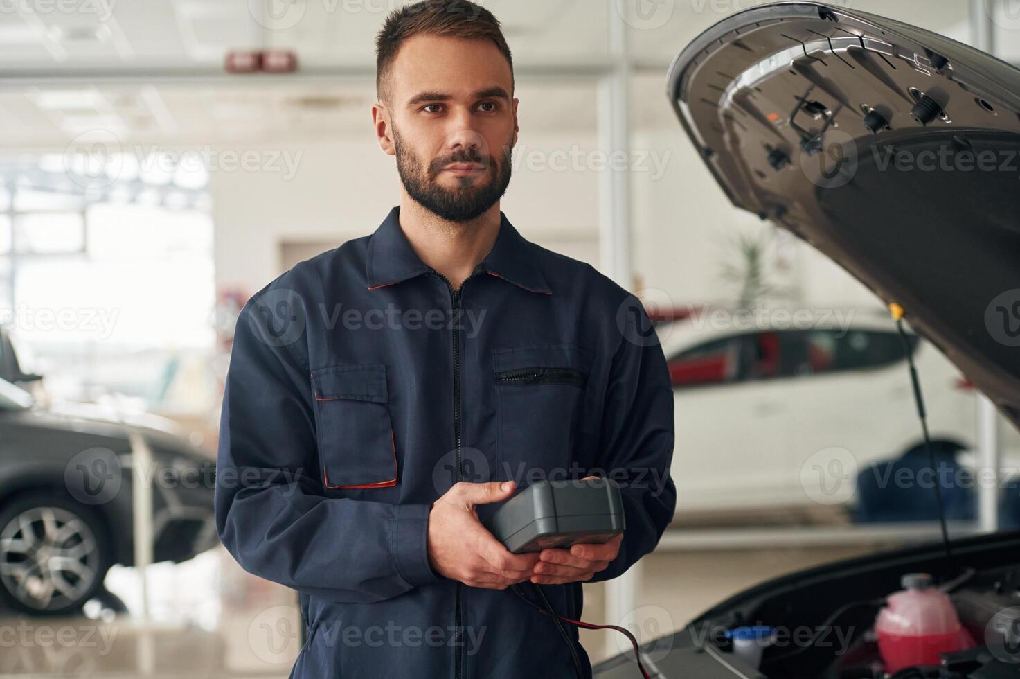 With device for ,measuring electricity. Car repairman is in the garage with automobile photo