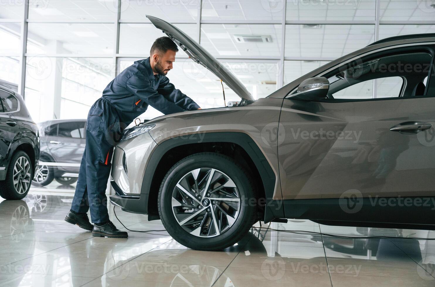 Focused on fixing, the vehicle. Car repairman is in the garage with automobile photo
