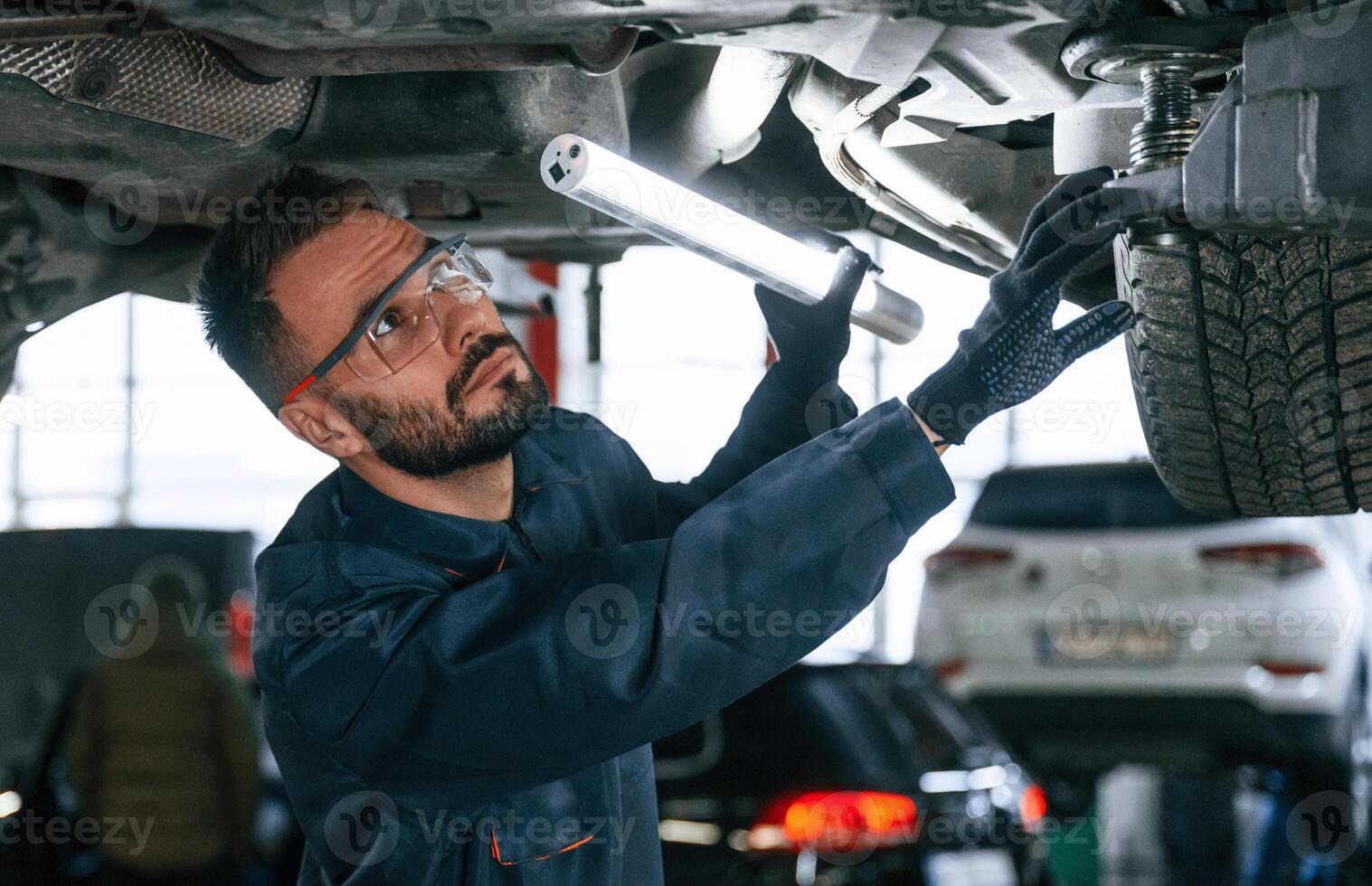 Under ,the, vehicle, fixing. Car repairman is in the garage with automobile photo
