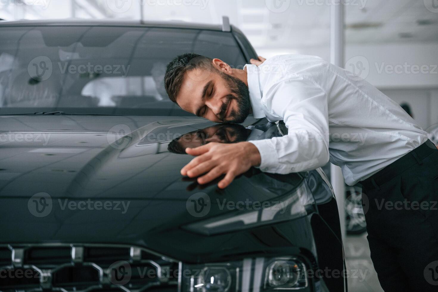 Embracing the ,car. Worker in formal clothes is in the auto salon photo