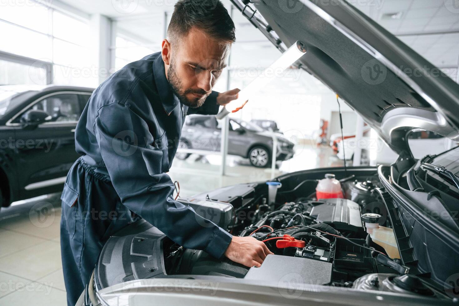 Busy car repairman ,is in the garage with automobile, fixing it photo