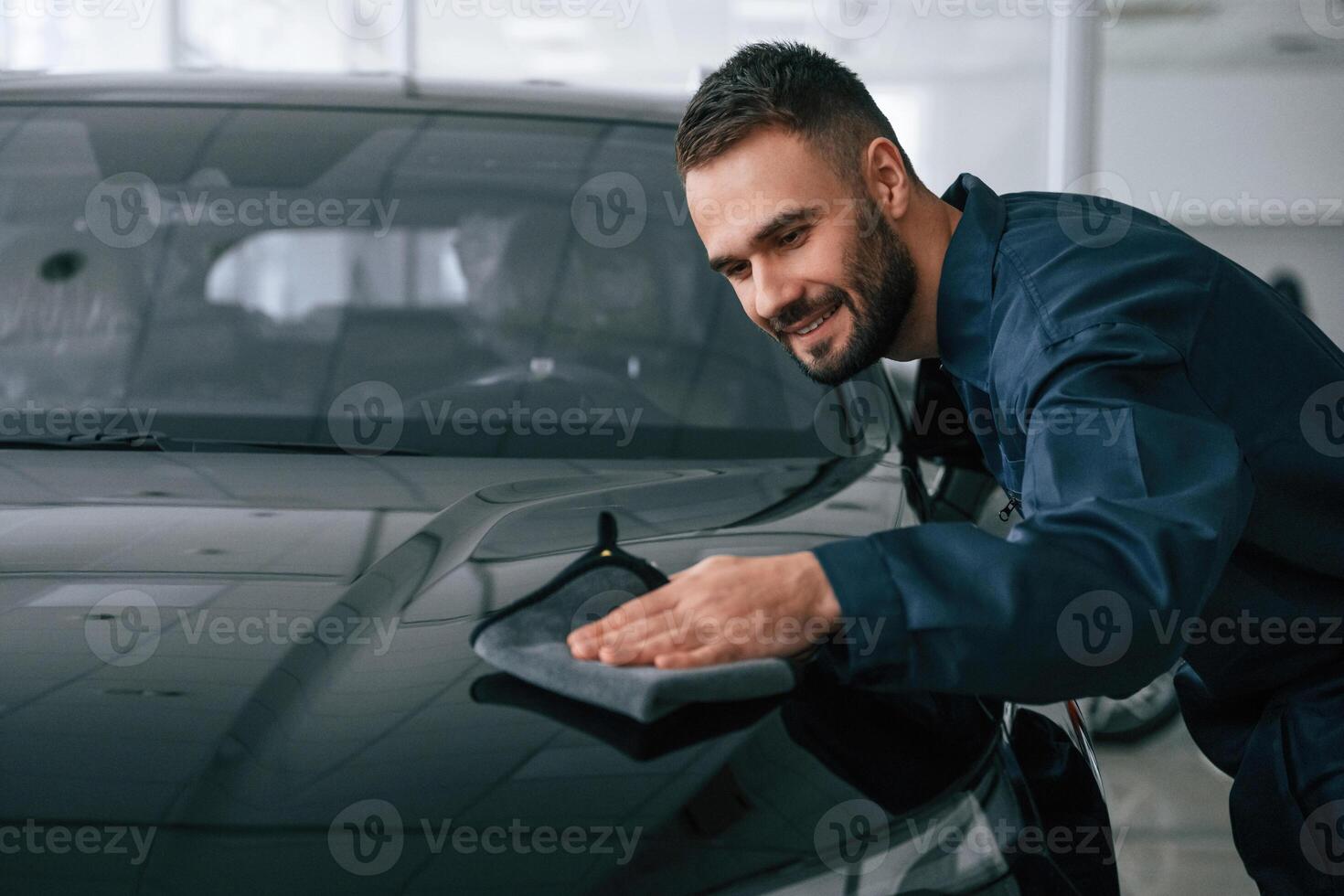 Process of, polishing the surface with cloth. Car repairman is in the garage with automobile photo