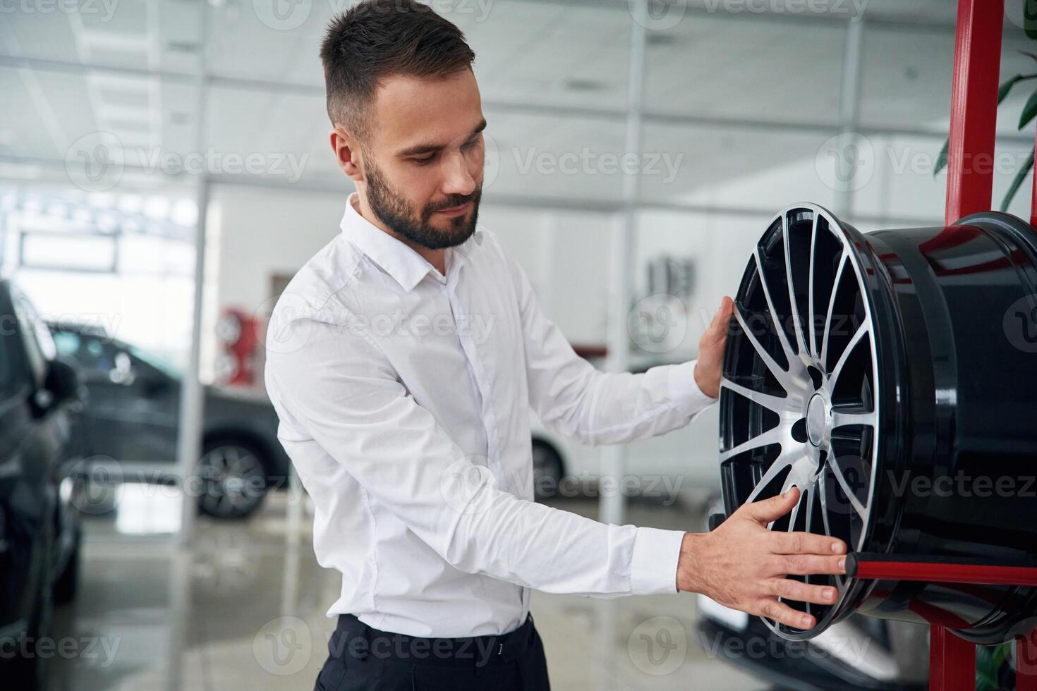 Worker, in formal clothes is in the auto salon photo