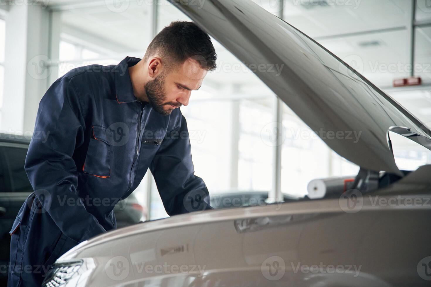 Side view, hood, is opened. Car repairman is in the garage with automobile photo