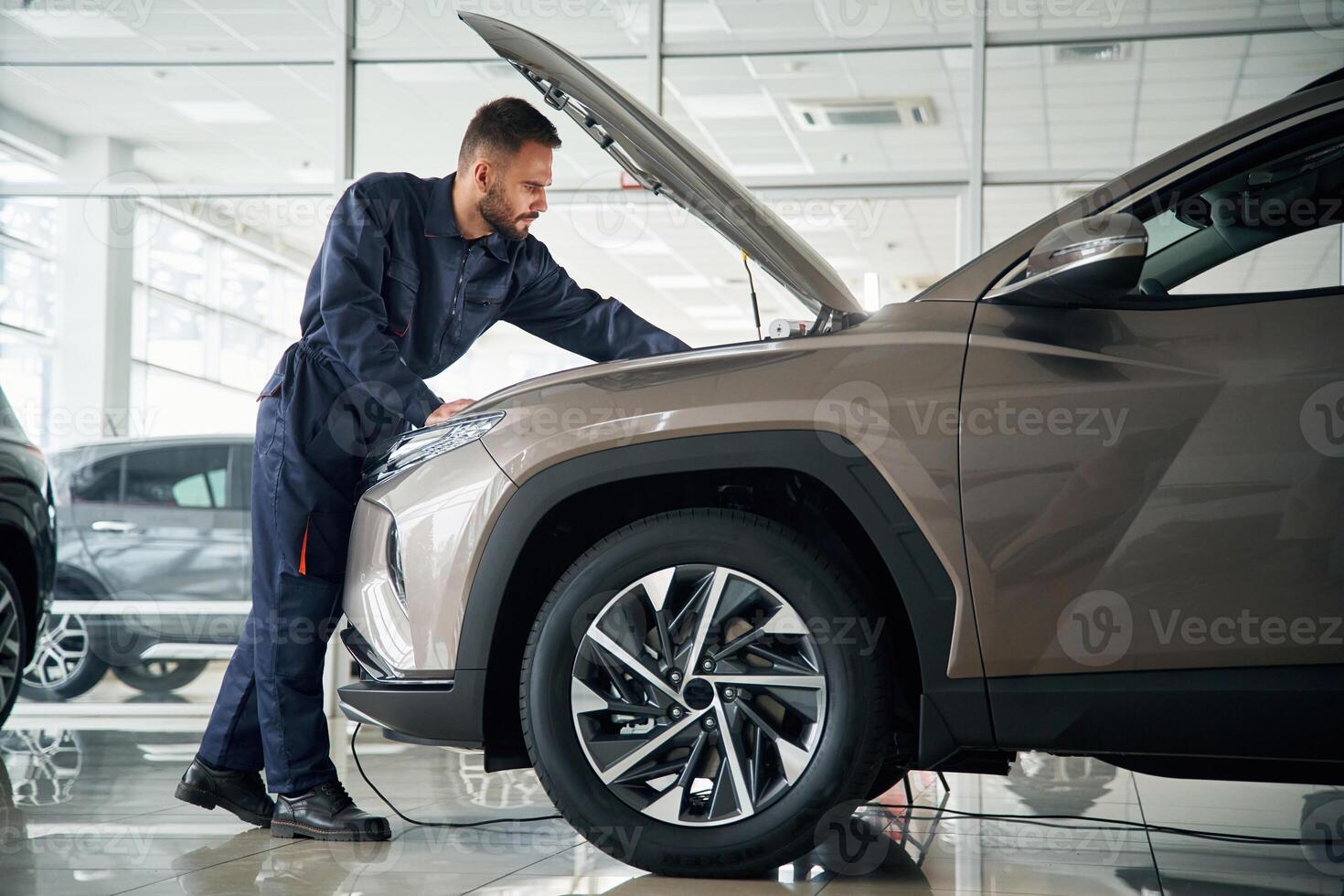 Fixing the vehicle. Side ,view. Car repairman is in the garage with automobile photo