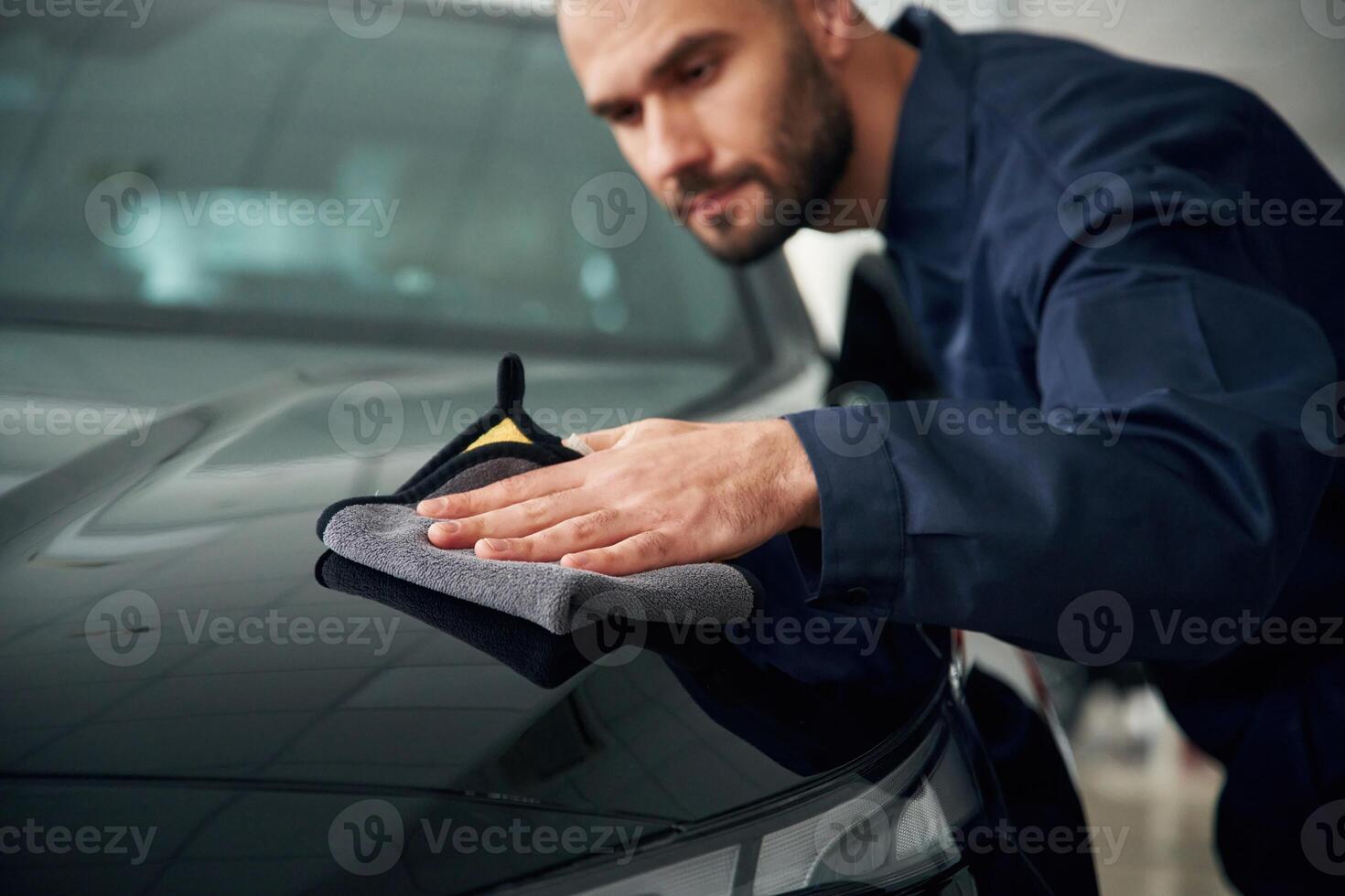 Process, of polishing ,the surface with cloth. Car repairman is in the garage with automobile photo