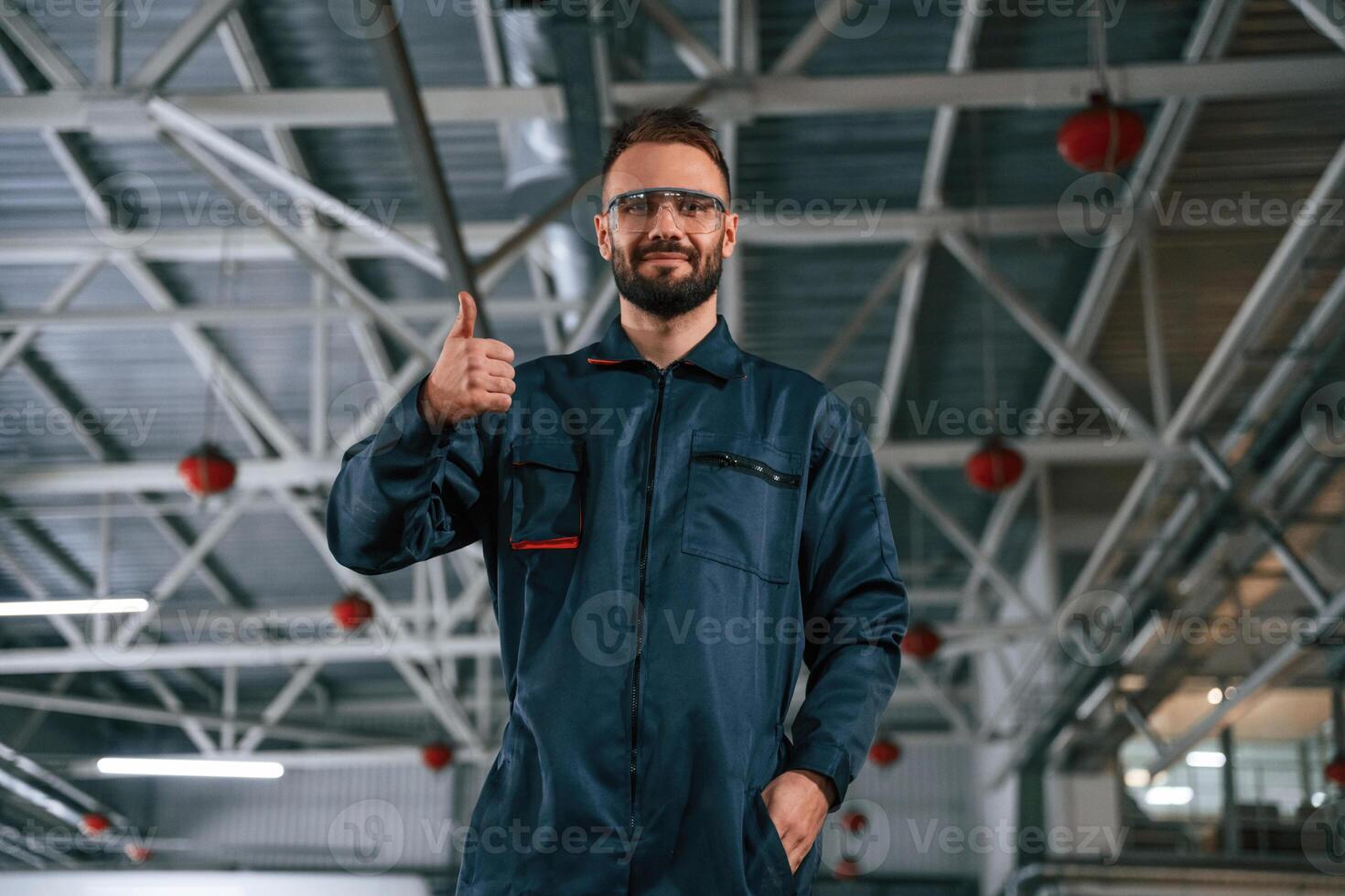 Standing, and posing,. Car repairman is in the garage with automobile photo