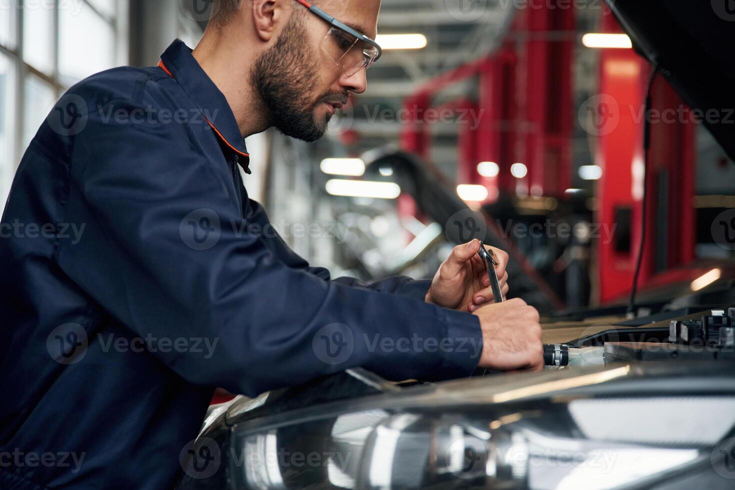 Hood is, opened, fixing. Car repairman is in the garage with automobile photo
