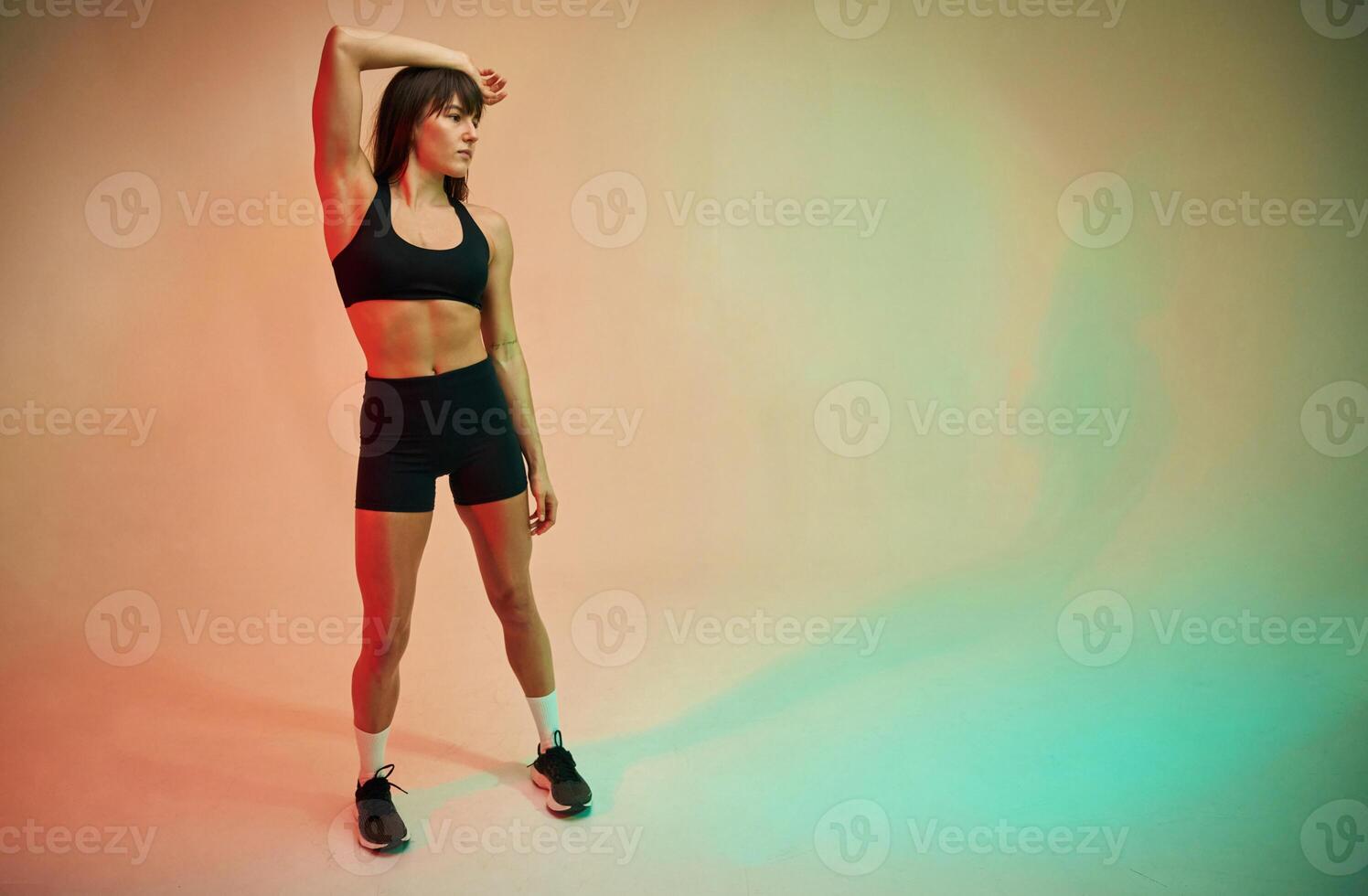 Standing and, doing ,,exercises. Young woman in fitness clothes is in the studio photo