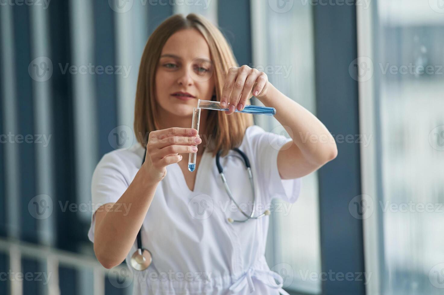 Test tubes, with liquid in them.. Female doctor in white coat is in the hall photo