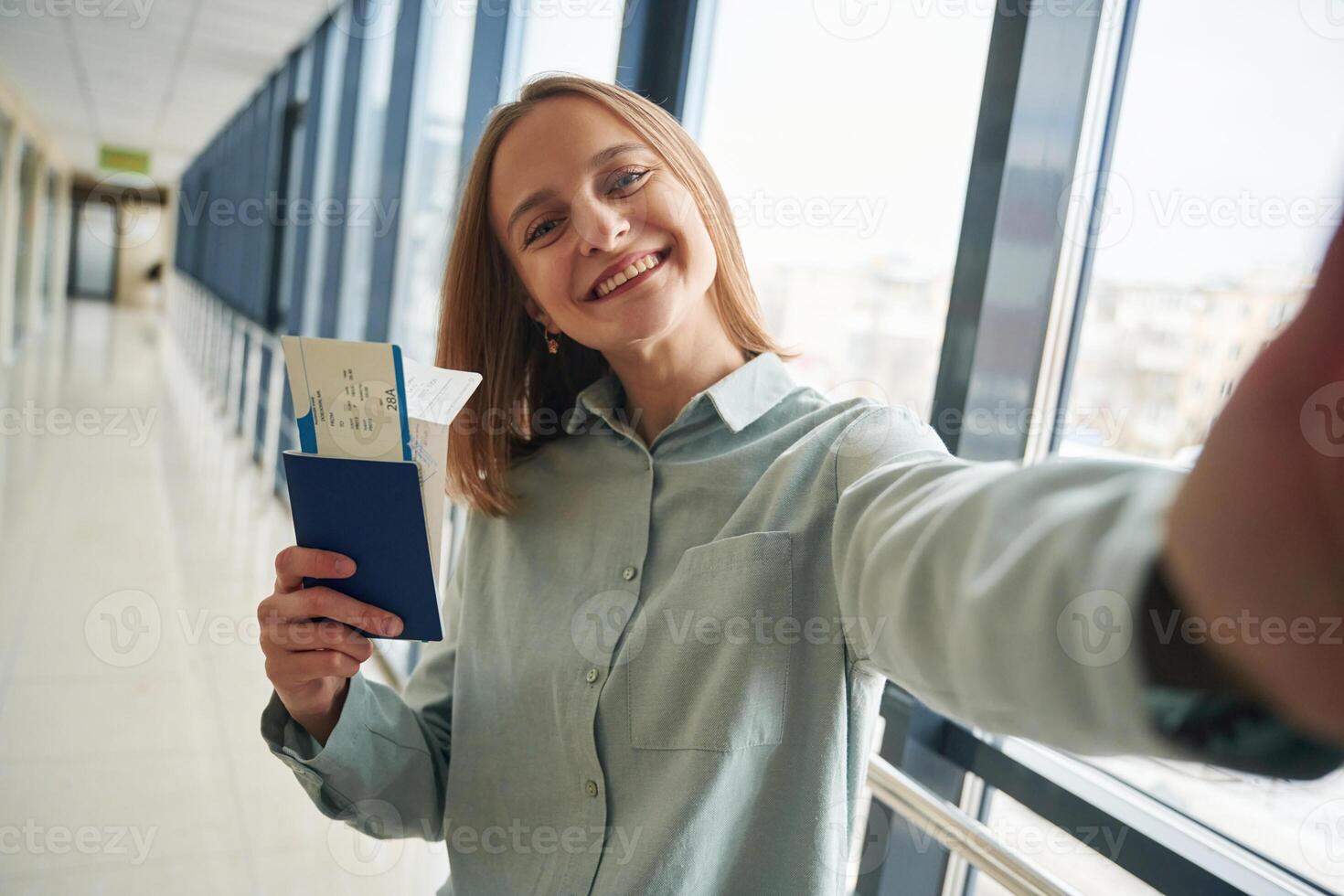 Making ,,selfie, holding tickets. Young woman in airport hall photo