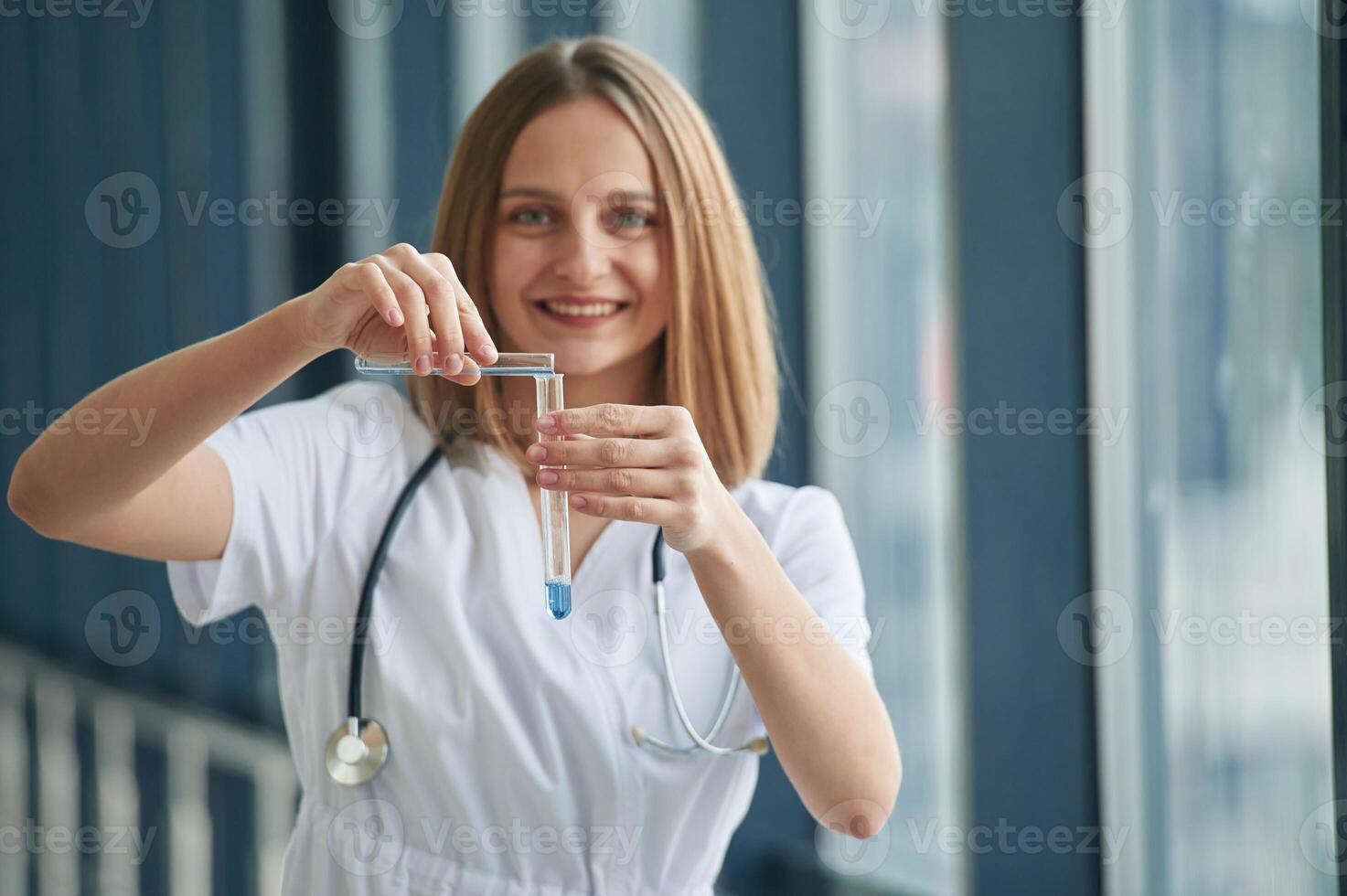 Test tubes, with liquid in them. Female doctor in white coat is in the hall photo