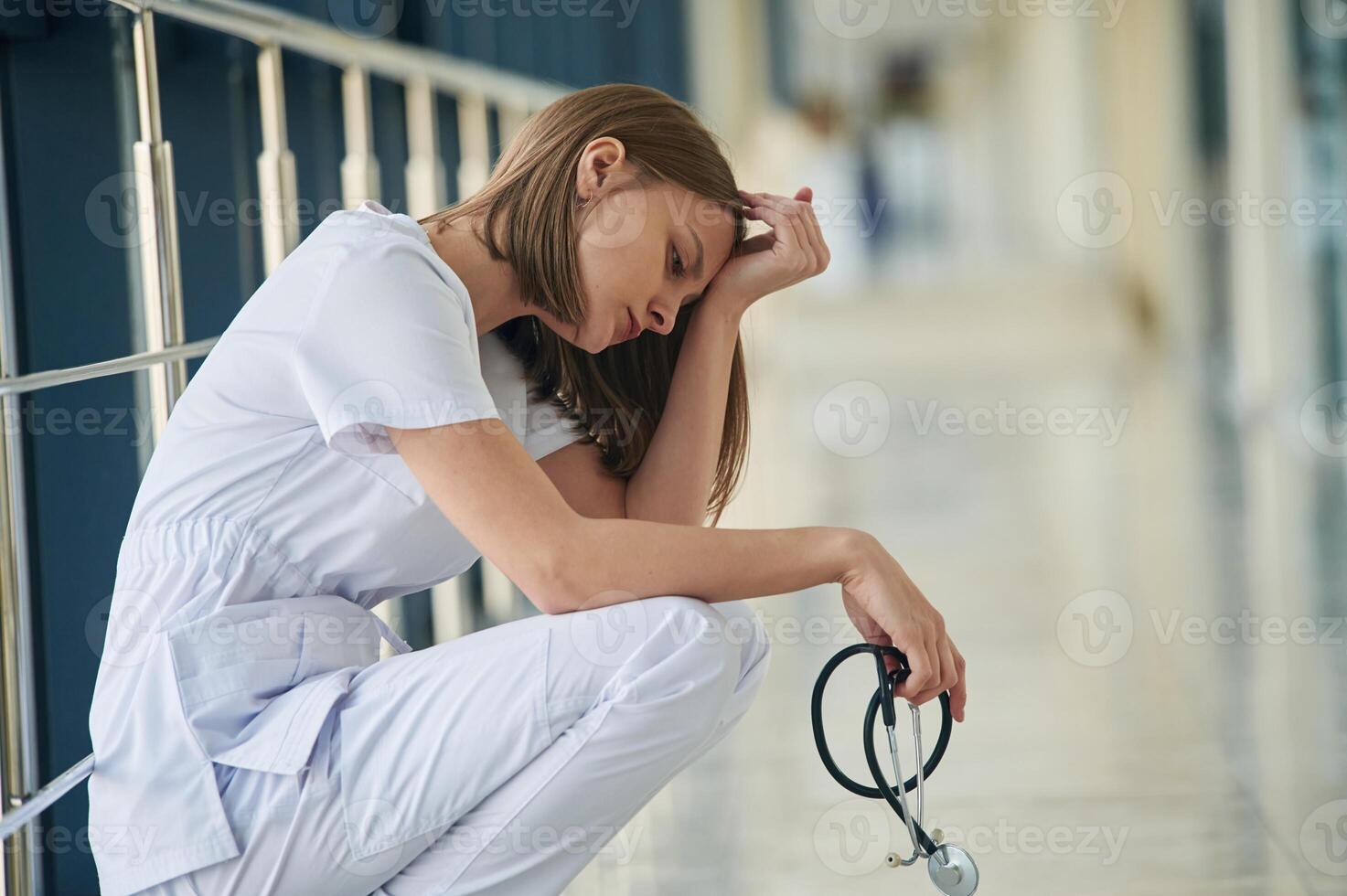 Sitting,, taking ,a break, tired. Female doctor in white coat is in the hall photo
