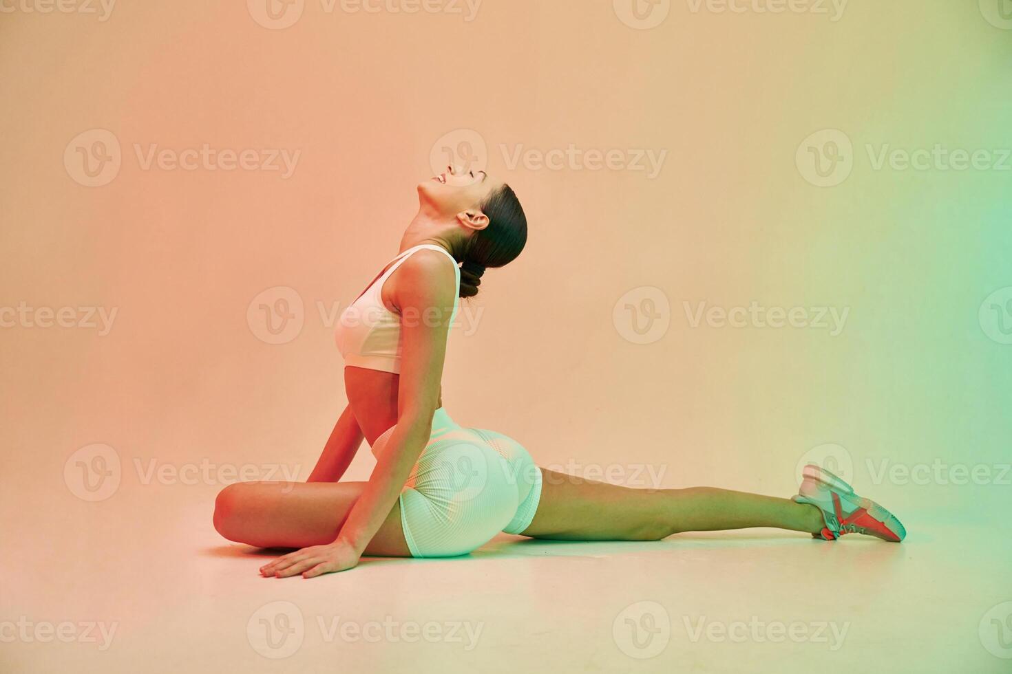Side ,view. Young fitness, woman ,in sportive clothes against background in studio photo