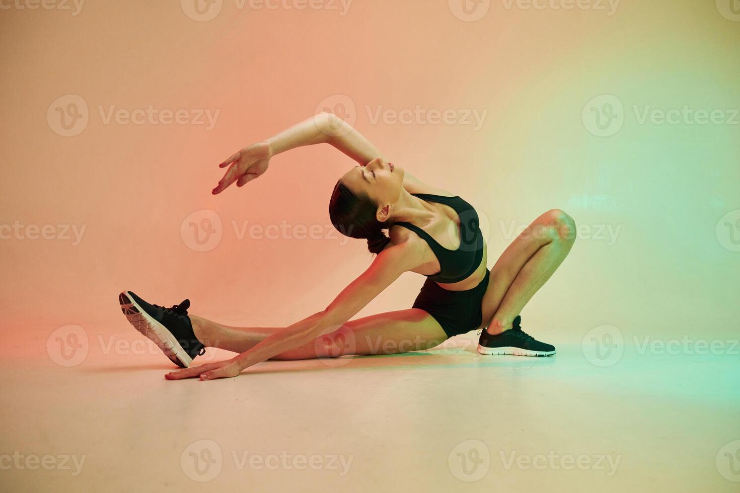 Showing flexibility. .Young fitness woman in sportive clothes against background in studio photo