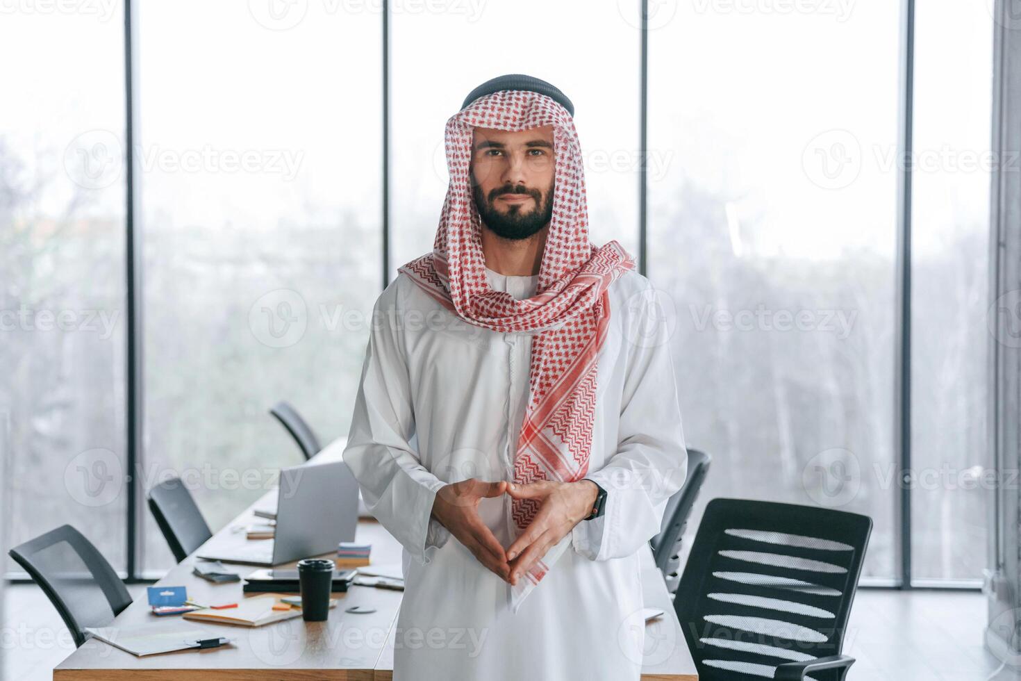 Against panoramic windows. Successful Muslim businessman in traditional outfit in his office photo