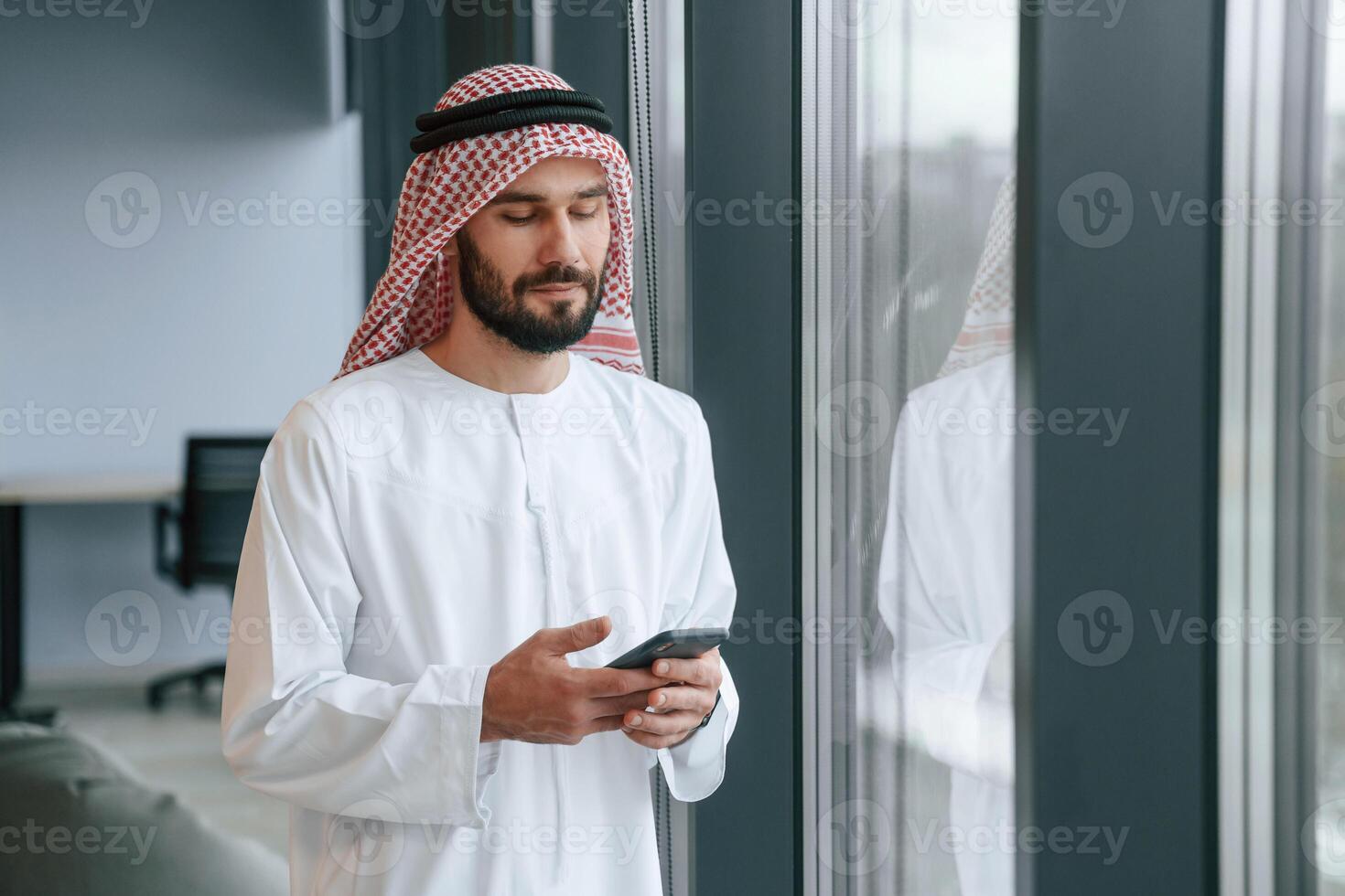 In ,the ,office with phone. ..Successful Muslim businessman in traditional outfit photo
