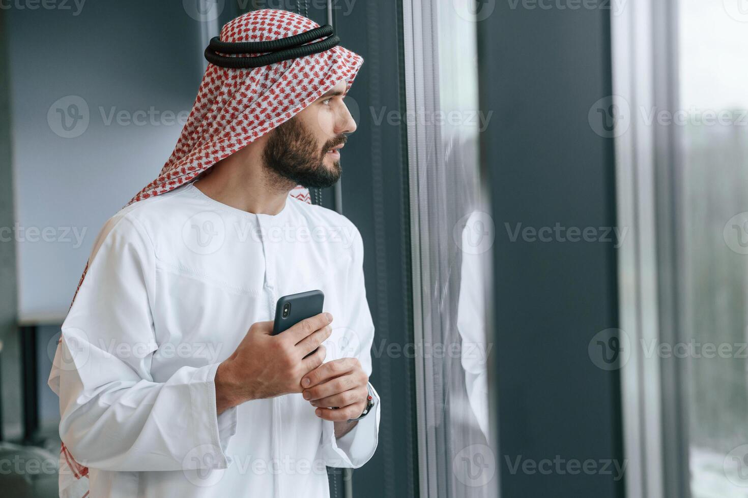 In the office with phone. Successful Muslim businessman in, traditional ,outfit photo