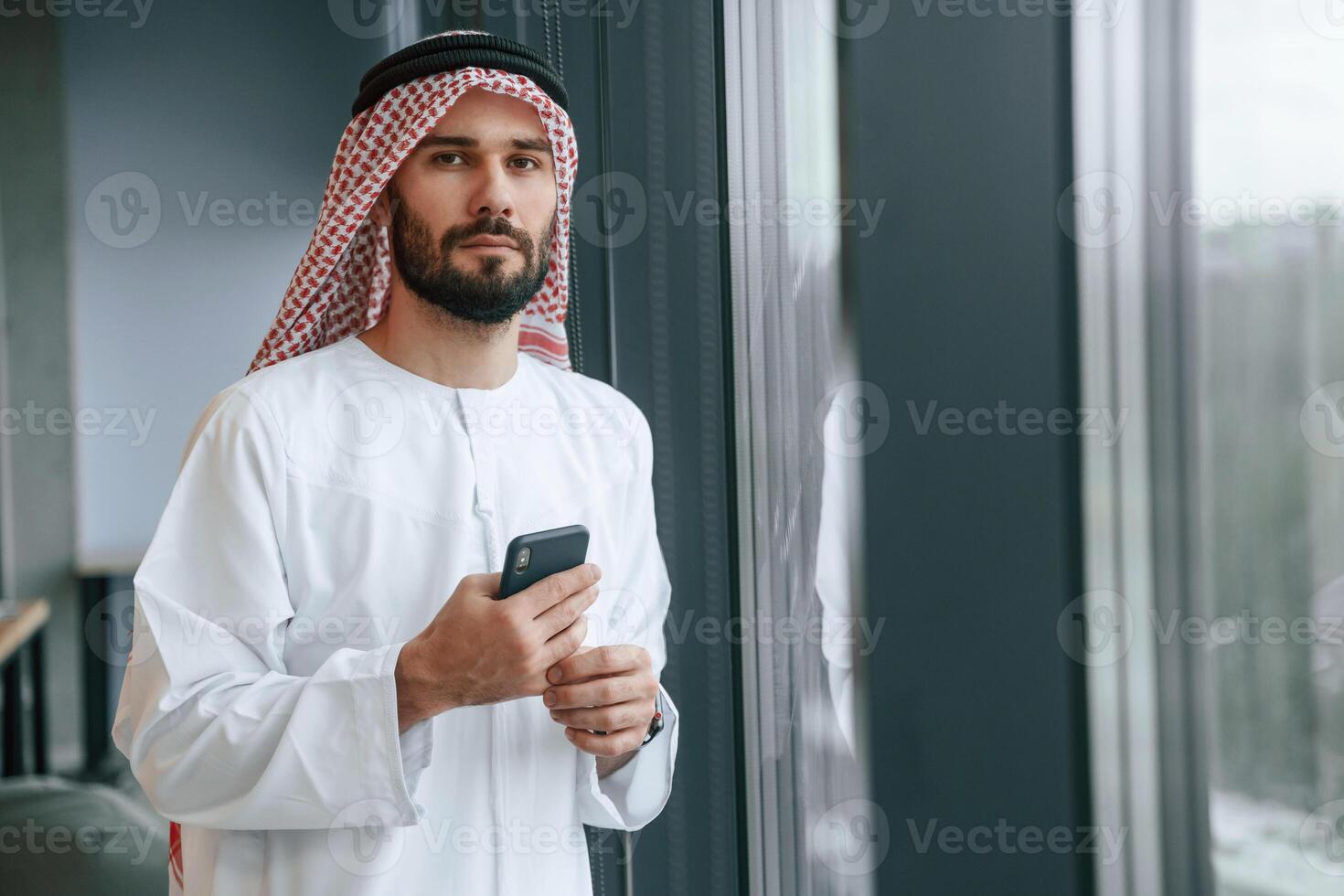 In the office with phone. Successful Muslim, businessman in, traditional outfit photo