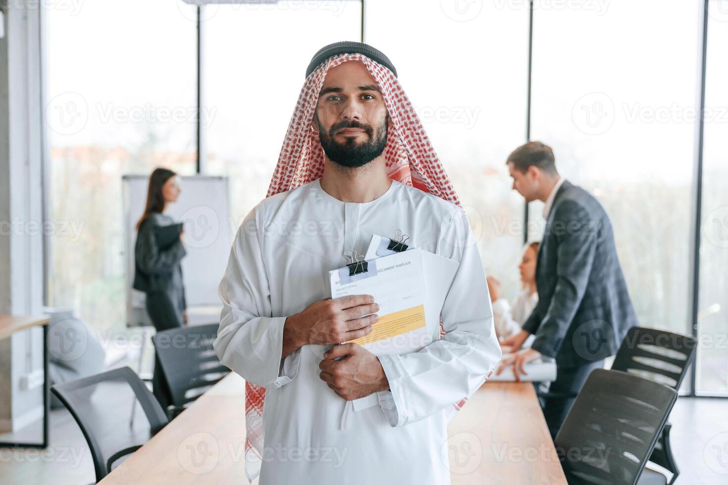 People,behind Muslim businessman that ,is, in traditional outfit with colleagues ,,in office photo