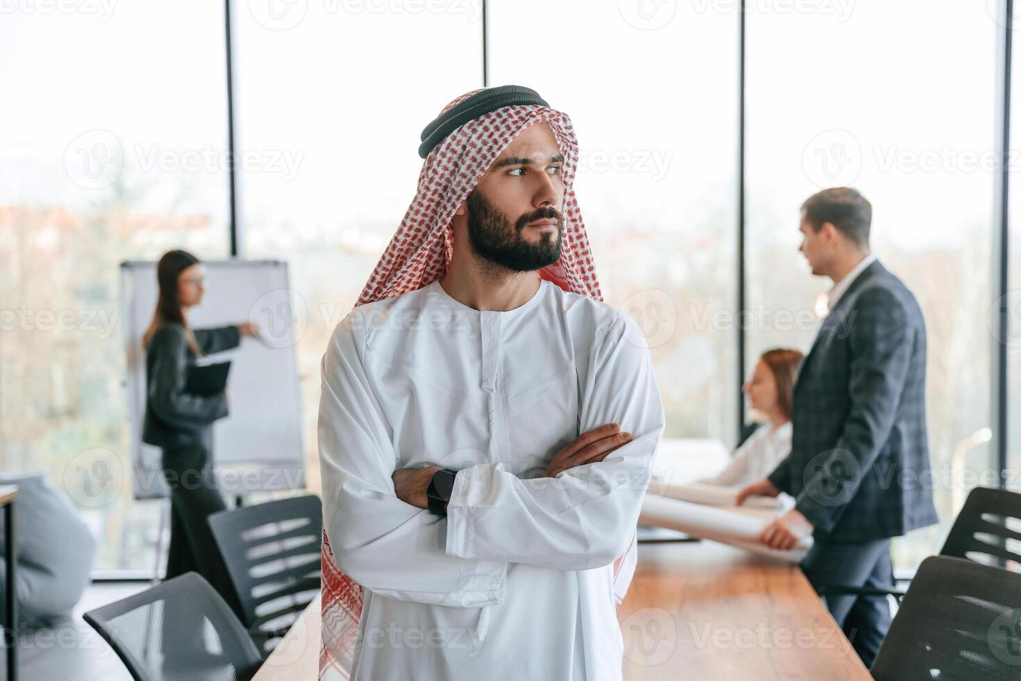 Standing in front of people that behind.. Muslim businessman in traditional outfit with colleagues in office photo