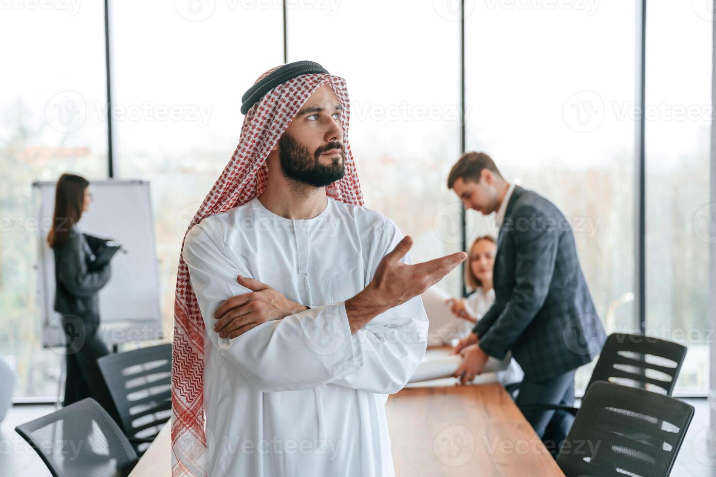 Standing in front, of, people that behind. Muslim businessman in traditional outfit with colleagues in office photo