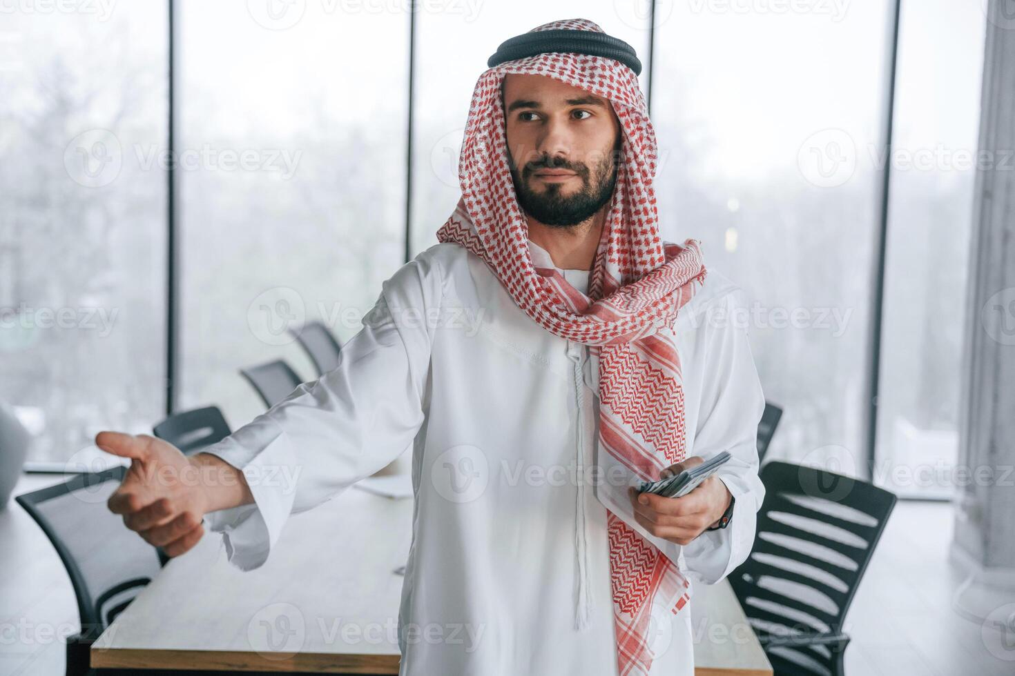 Holding ,money in hands. Successful Muslim businessman in traditional outfit in his office photo