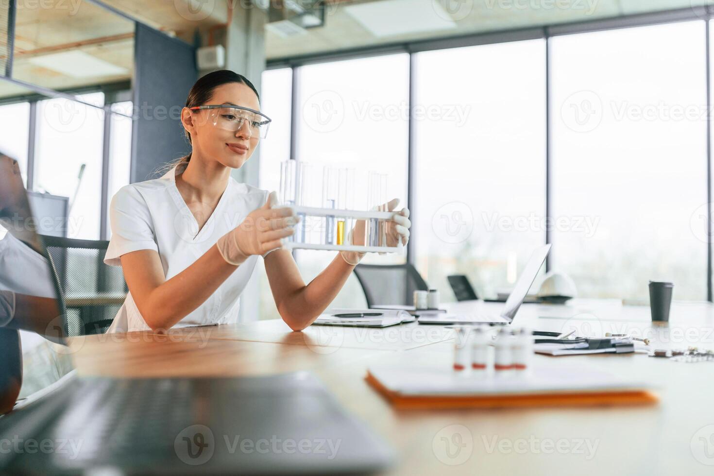 Working, with, bunch, of, test tubes. Female doctor in white coat is indoors photo