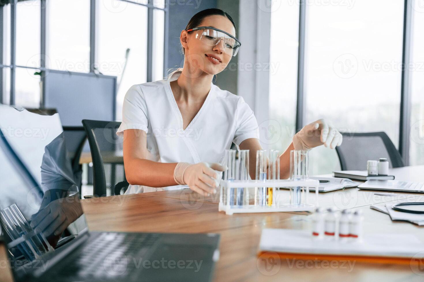 Many of, the, test tubes with liquid on the table. Female doctor in white coat is indoors photo