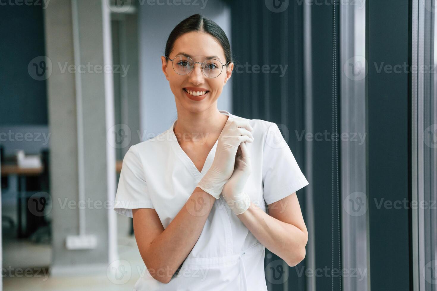 Cheerful female doctor in white coat is indoors standing and smiling photo