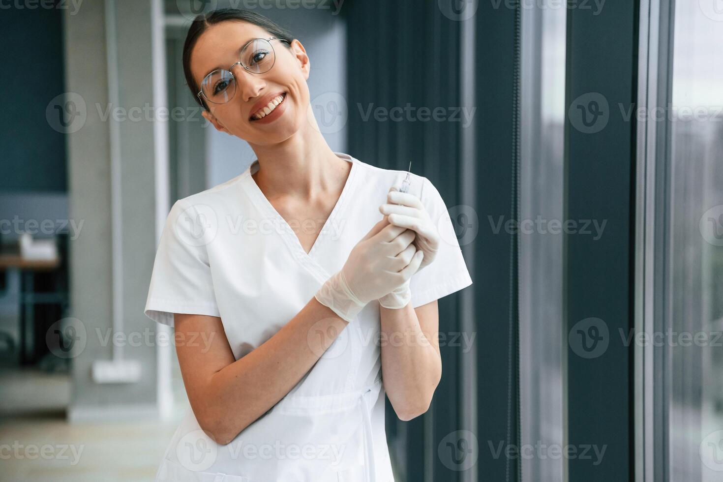 Syringe,, in hands. Female doctor in white coat is indoors photo