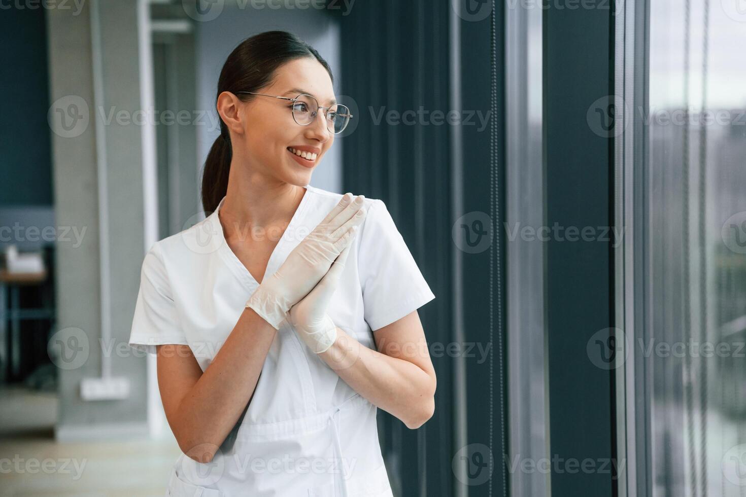 Cheerful, female, doctor in white coat is indoors standing and smiling photo
