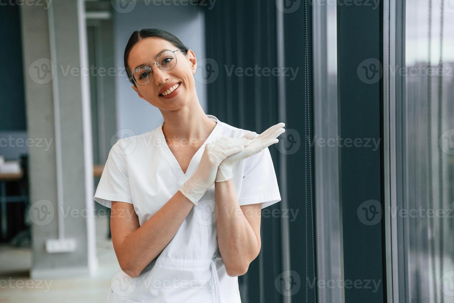 Cheerful ,female doctor in white coat is indoors standing and smiling photo
