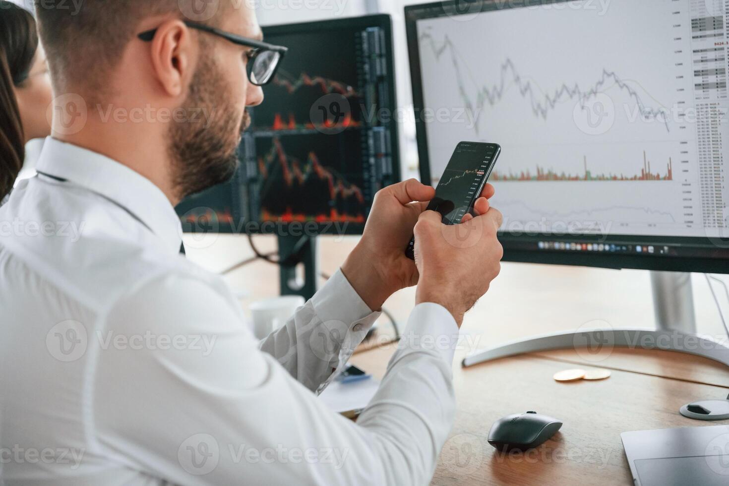 Holding smartphone in hands.,, Businessman is sitting by computer and working in the office photo