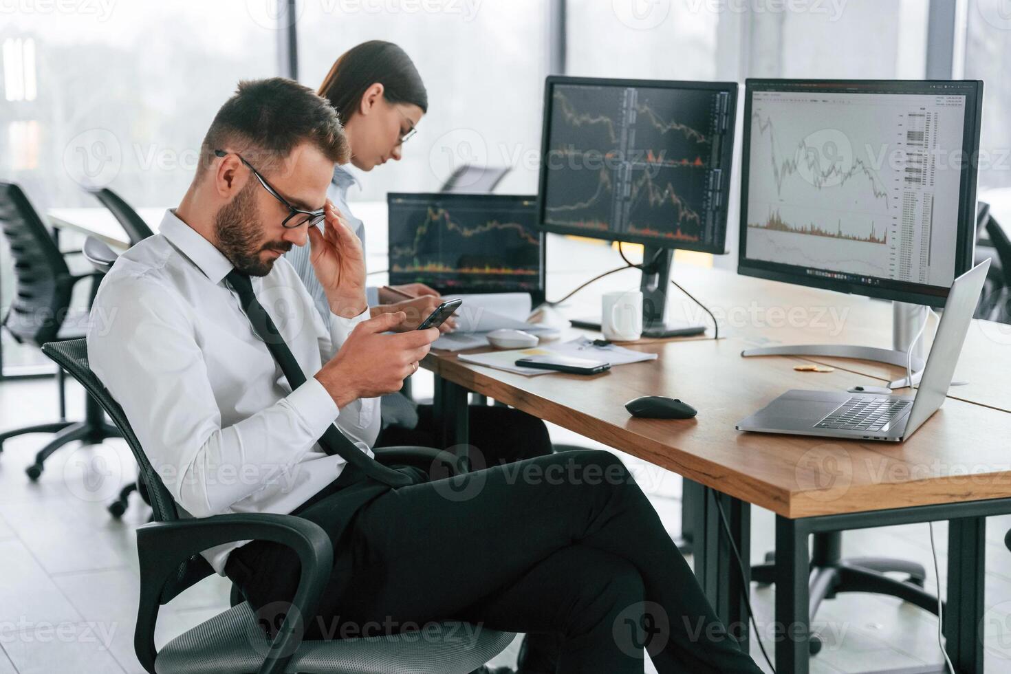 Man, is using ,smartphone. Two employees are working in the office together photo