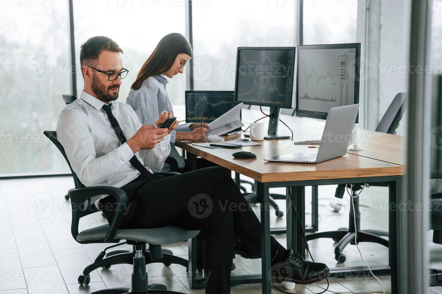 Man is using, smartphone. Two employees are working in the office together photo