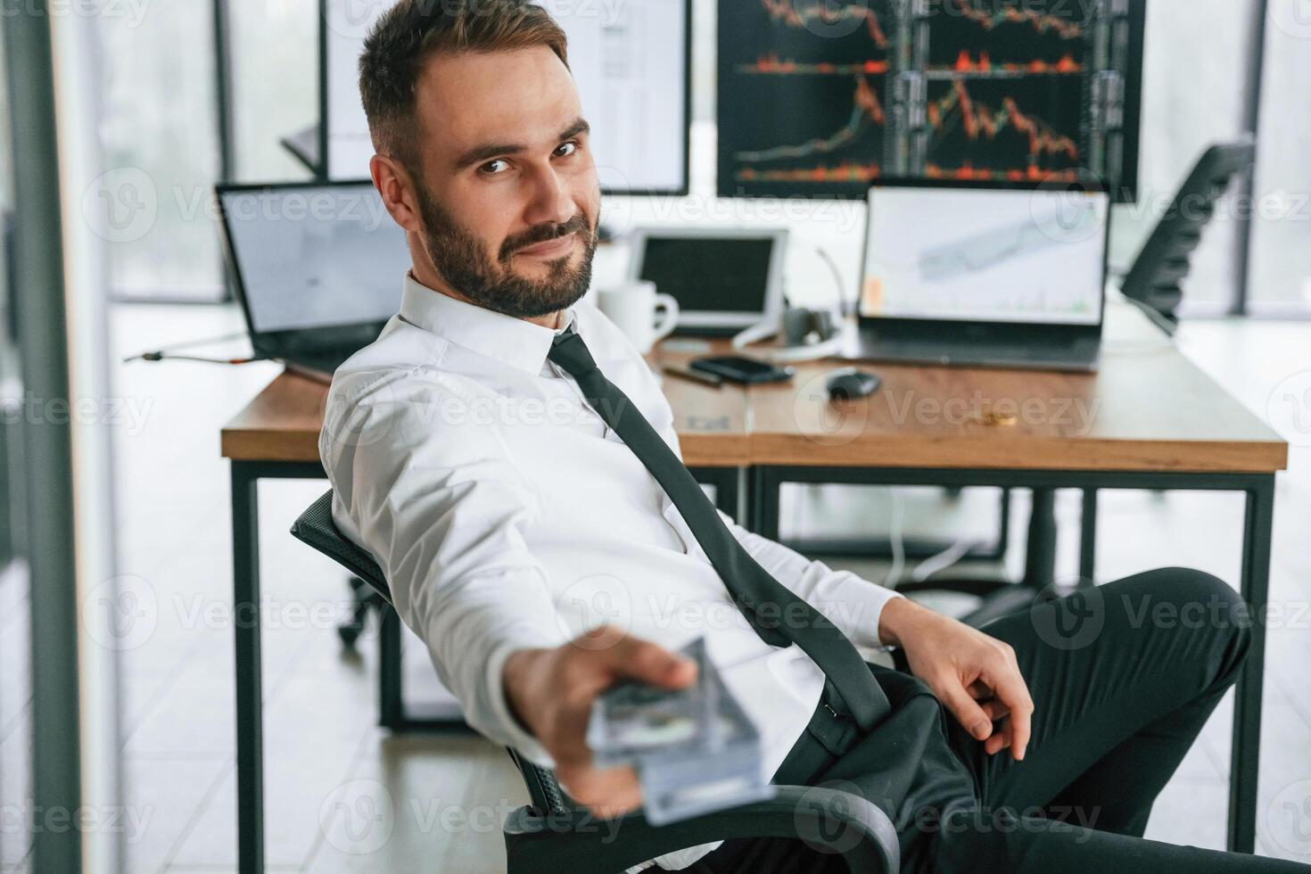 Giving lot of money.,. Holding in hand. Businessman is sitting by computer and working in the office photo