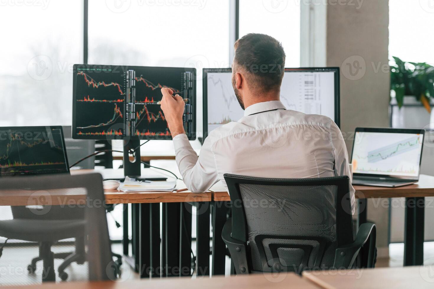 Rear, view. Businessman is sitting by computer and working in the office photo