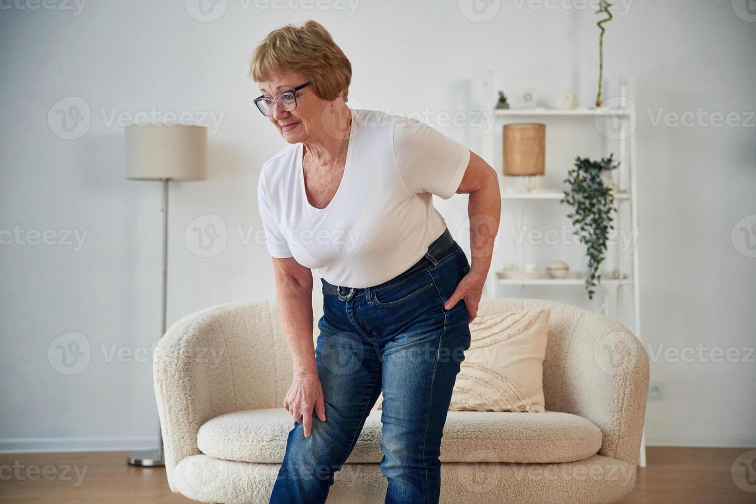 Pain ,in the leg. Senior elderly, woman is at home in the living room photo